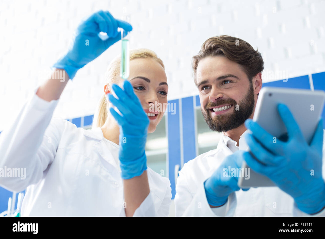 Dispositivo moderno. Nice positivo uomo gioioso foratura di un tablet e guardando la provetta mentre si lavora insieme con il suo collega Foto Stock