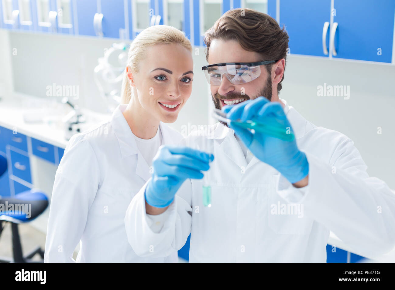 Progetto chimica. Nice positivo chimici intelligenti in piedi insieme e sorridenti mentre si lavora su un progetto di chimica Foto Stock