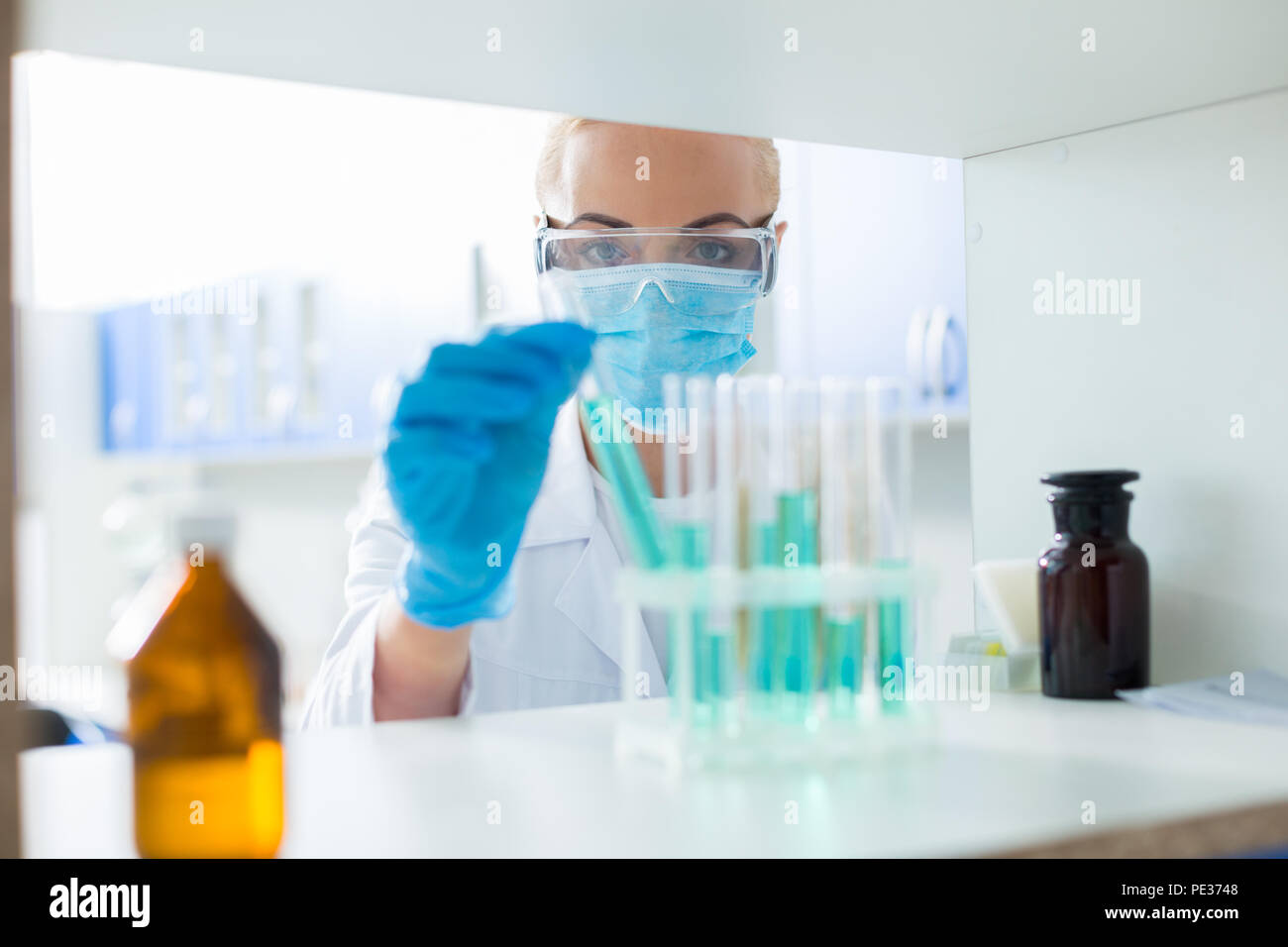 Gli sviluppi scientifici. Grave nice ricercatore scientifico guardando le provette e assunzione di uno di loro durante il lavoro in laboratorio Foto Stock