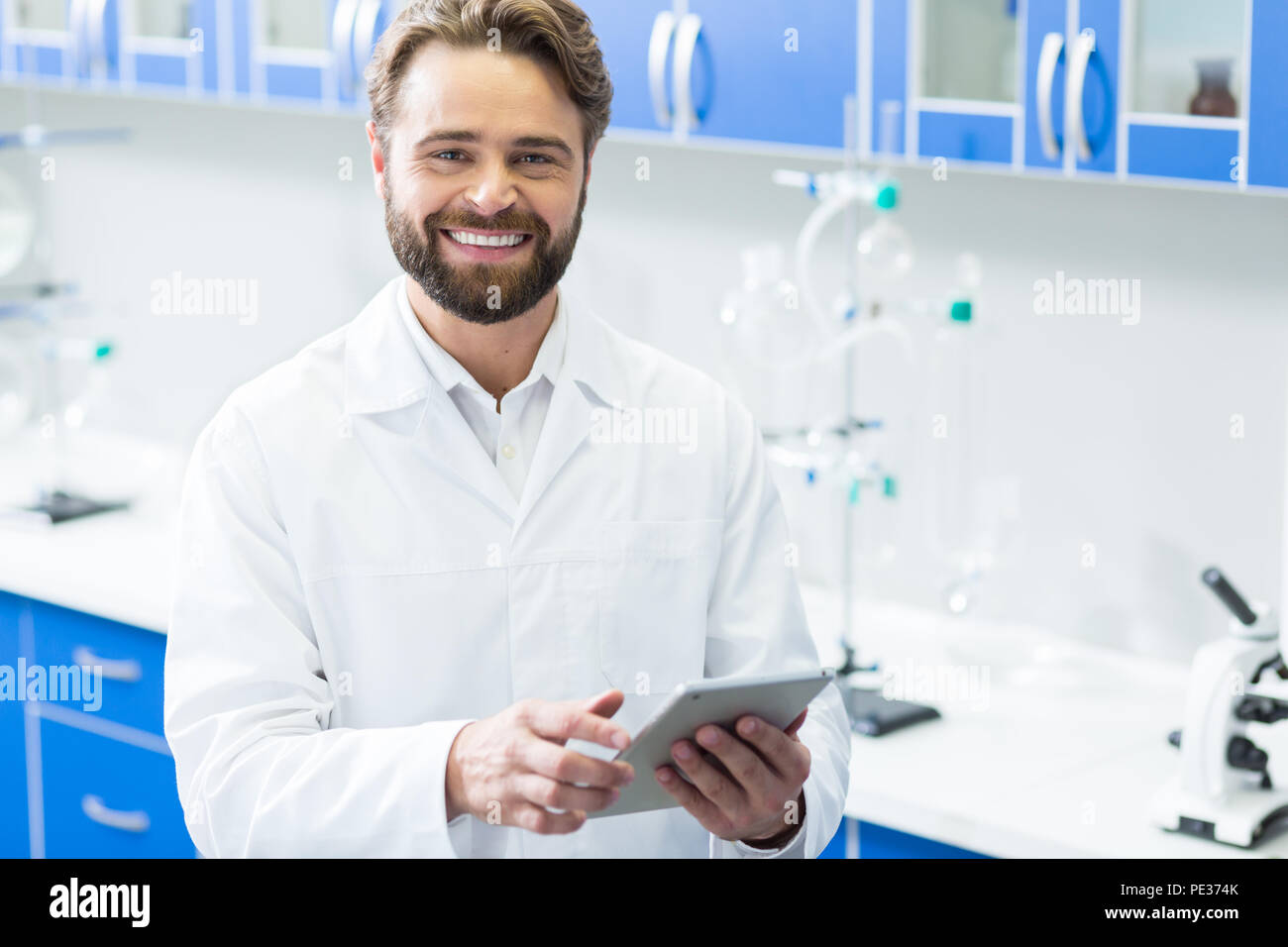 Stato d'animo positivo. Felice bello bello biologo sorridente e guardando a voi mentre si tiene una scheda lasciare in mano Foto Stock