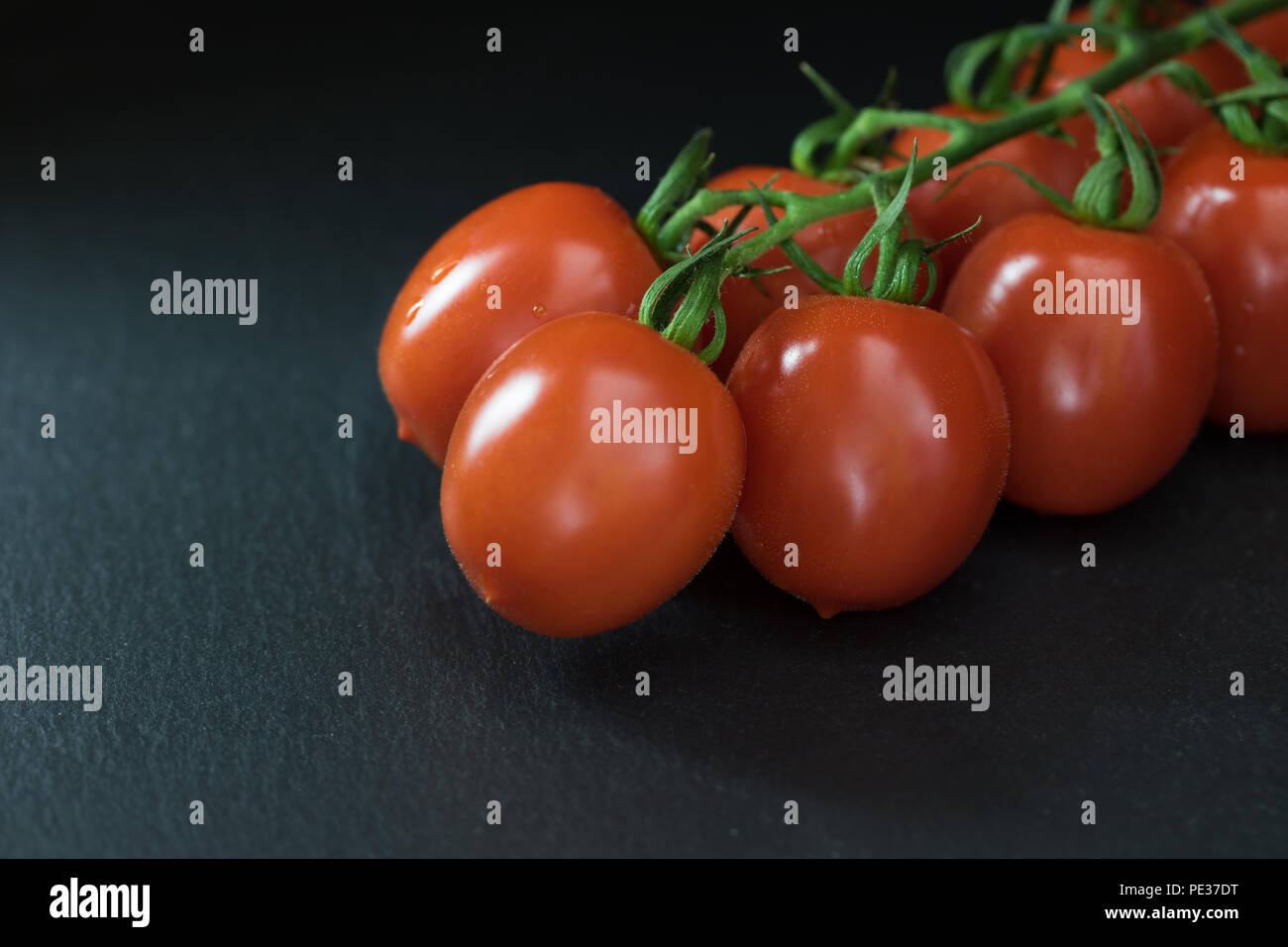 Tasto basso shot con un mezzo di arbusti pomodori giacente sulla pietra nera tabella. Non vi è posto per il testo sulla foto. Foto Stock