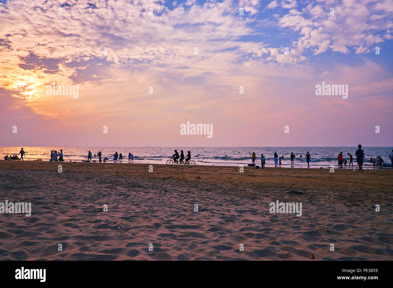 La spiaggia di sabbia sulla Baia del Bengala con le sagome delle persone in viola la luce del tramonto, Chaung Tha, Myanmar. Foto Stock