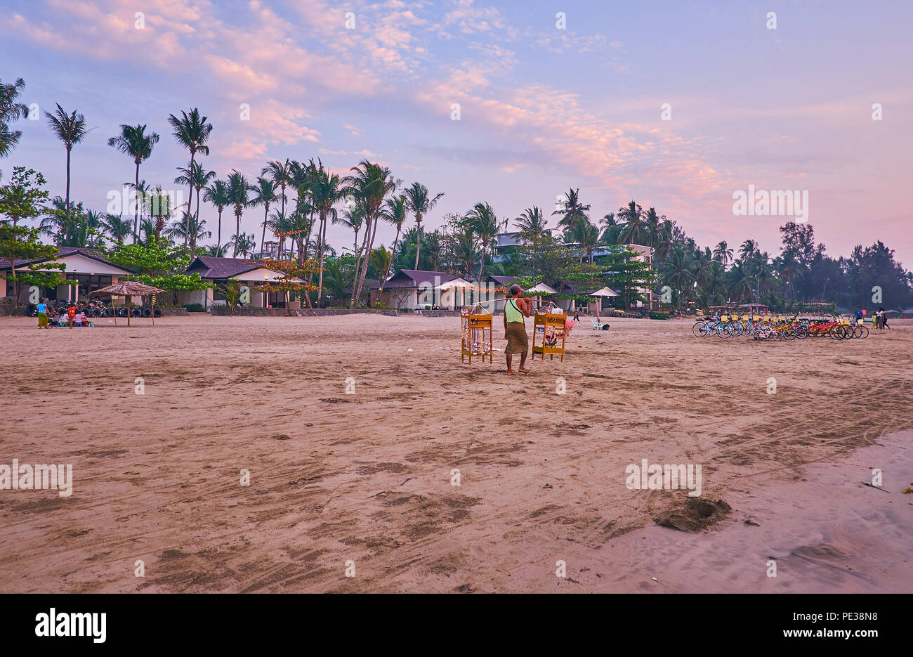 CHAUNG THA, MYANMAR - 28 febbraio 2018: il venditore ambulante di souvenir passeggiate lungo il Golfo del Bengala a riva con vista sulla fila di spiaggia bungalow su backg Foto Stock
