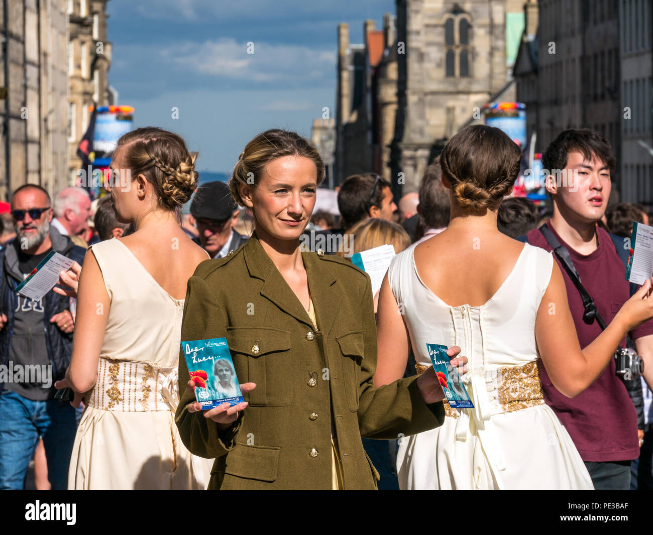 Bella femmina Fringe performer nella II Guerra Mondiale costume di cari Lucy mostra distribuendo volantini, Royal Mile di Edimburgo, Scozia, Regno Unito durante il festival Foto Stock