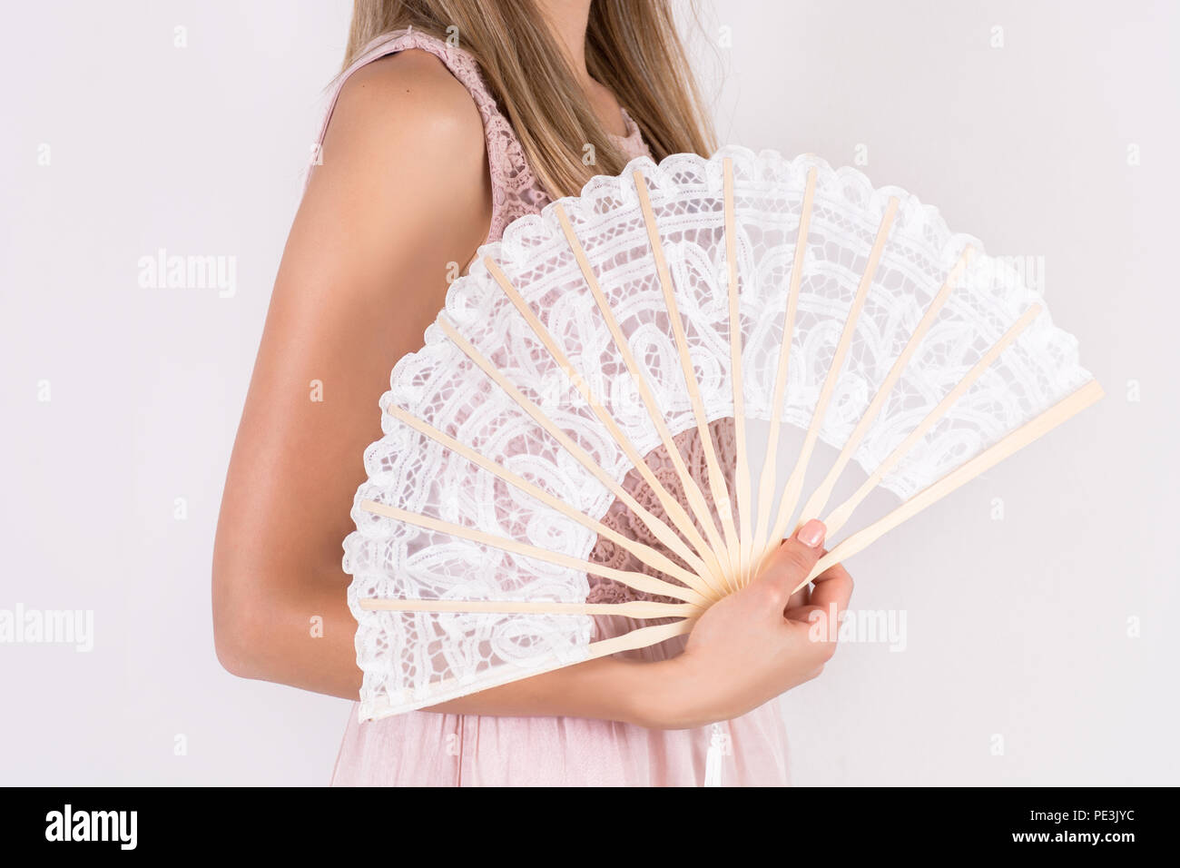 Giovane e bella ragazza con pizzo bianco Ventilatore a mano isolato su sfondo per studio. In estate il concetto di calore. Close up, il fuoco selettivo Foto Stock