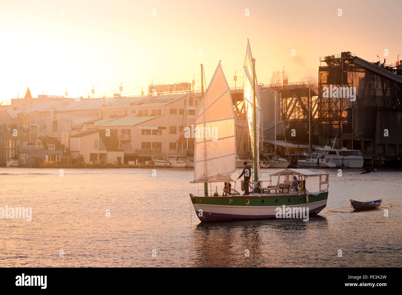 Barche a vela che entrano in porto vicino a Granville Island,Vancouver, con il sole che tramonta sullo sfondo. Foto Stock