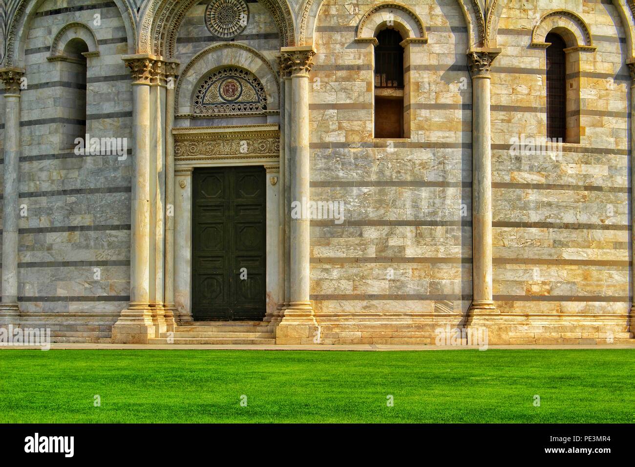 Una vista della porta e gli elementi della facciata e la decorazione esterna del Battistero di Pisa, Italia Foto Stock