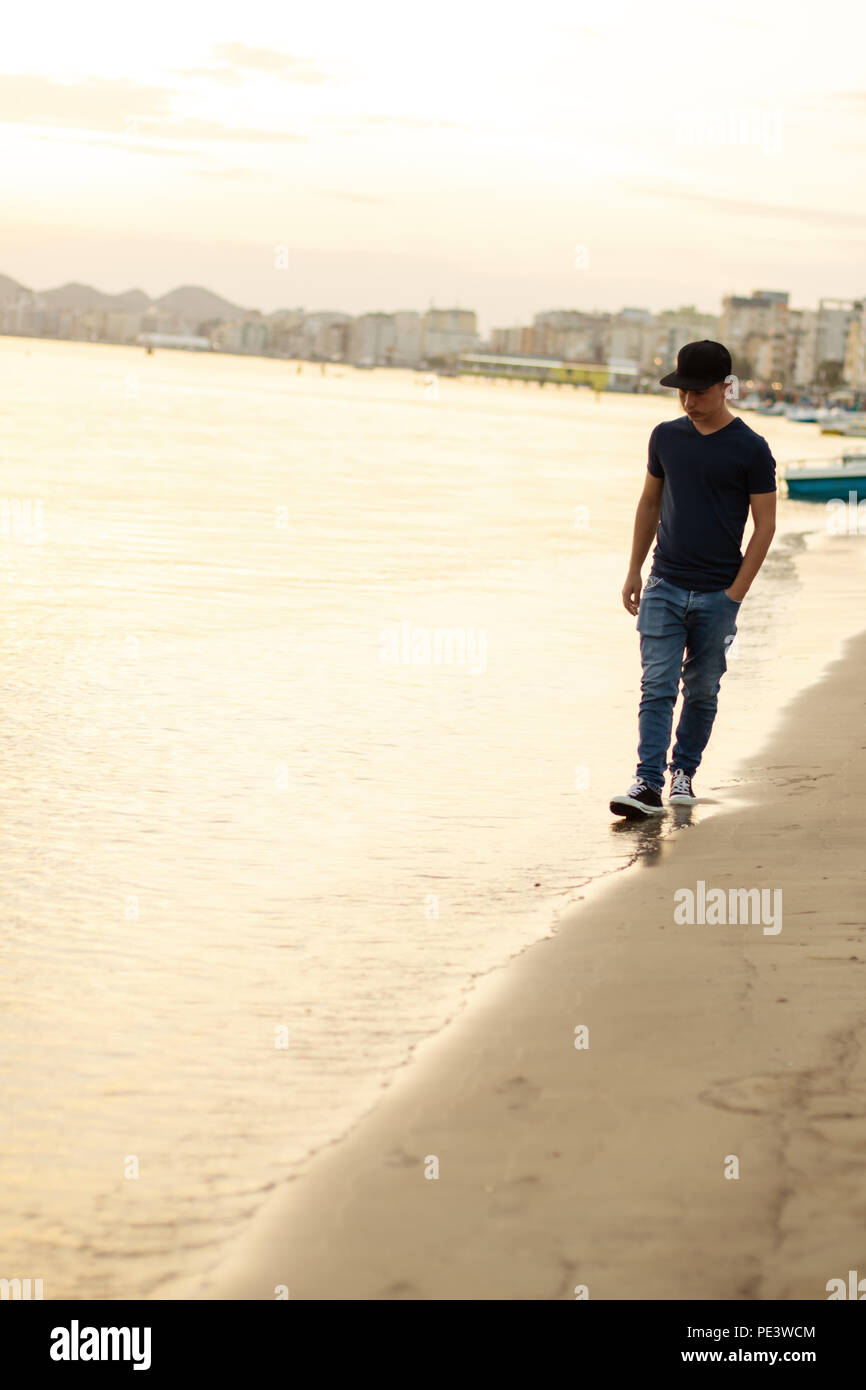 Young Teen passeggiando lungo la riva della spiaggia al tramonto di sera Foto Stock