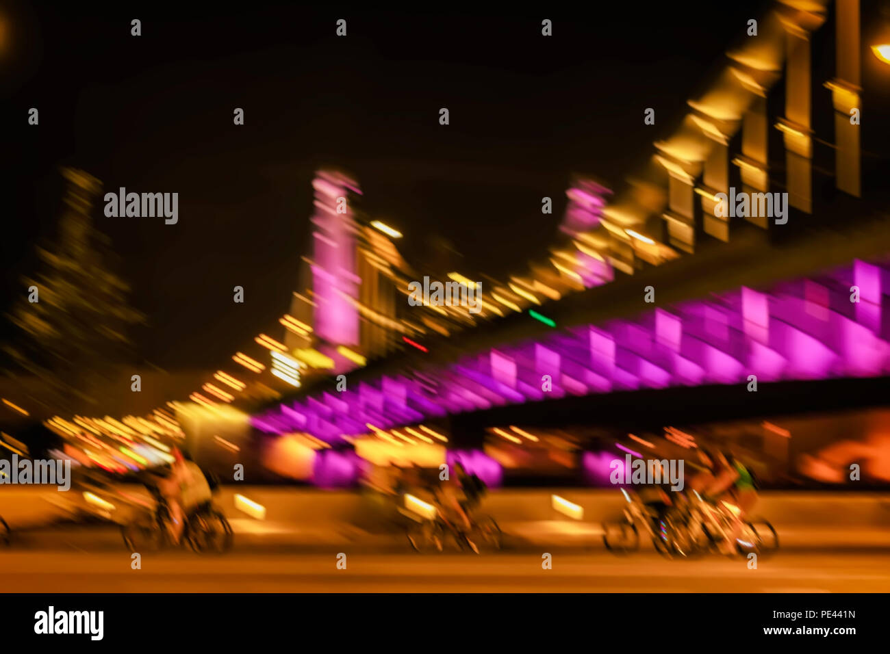 Movimento immagine sfocata di cavalcare i ciclisti sagome su un ponte luminoso sfondo, città illuminazione notturna, motion blur. Concetto moderno di stile di vita sano Foto Stock
