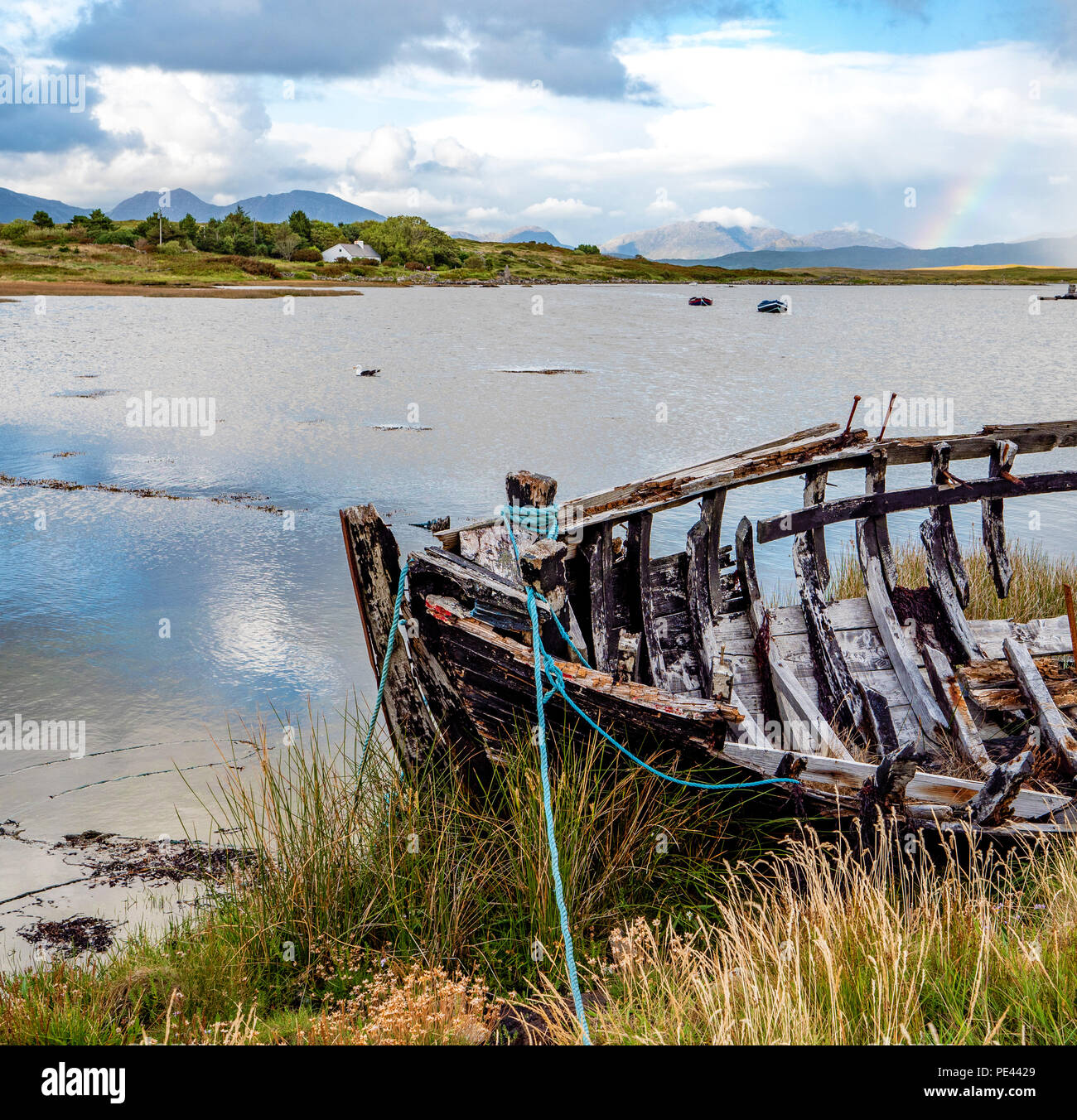 Prua del relitto di una barca con Twelve Ben al di là dell'isola se Inishnee vicino Roundstone sulla costa del Connemara Irlanda Foto Stock