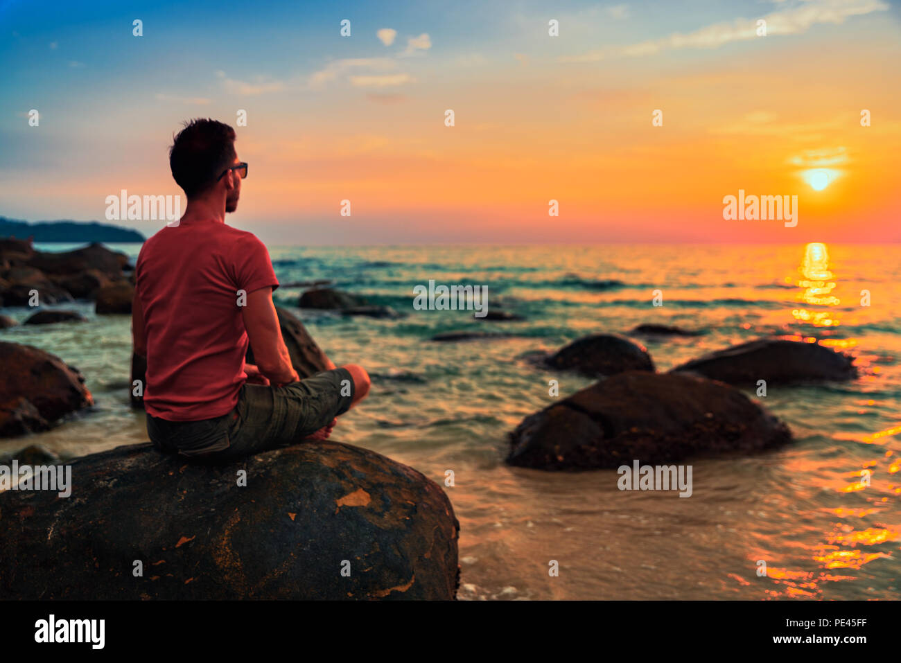 Persone che praticano lo Yoga posa e la meditazione sulla spiaggia tropicale al tramonto Foto Stock