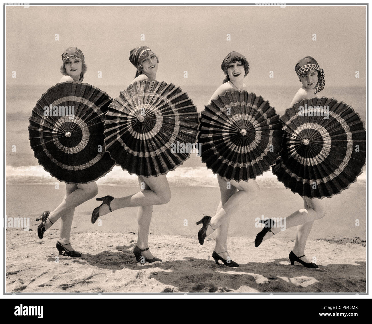 1920's Vintage la balneazione Belles ' enca delle ragazze in posa con ombrelloni su di una spiaggia di sabbia Foto Stock