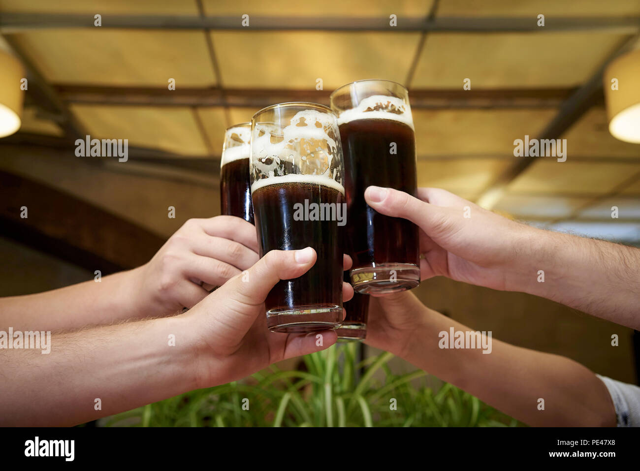 Gli uomini con le mani in mano con bicchieri di birra. Foto Stock