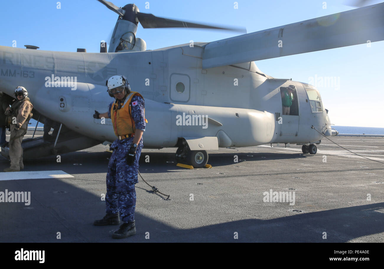 Un membro del Giappone Maritime Forze di autodifesa dirige i passeggeri su un U.S. MV-22 Osprey sul ponte di volo della nave giapponese Hyuga durante l'esercizio Alba Blitz 2015 al largo delle coste Marine Corps base Camp Pendleton, California, Sett. 4, 2015. Alba Blitz è una multinazionale esercizio di formazione progettate per migliorare Expeditionary Strike gruppo tre e 1° Marine Expeditionary Brigade la capacità di condotta mare-basando le operazioni, gli sbarchi anfibi e il comando e le capacità di controllo a fianco di coalizione. Foto Stock