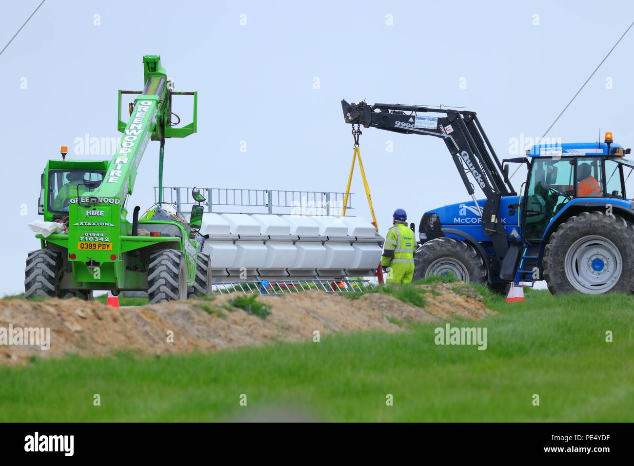 2 macchine lavorano insieme per posizionare una sezione di un trasmettitore pronto per essere sollevato al di sopra del montante temporanea a Emley Moor in elicottero gru. Foto Stock