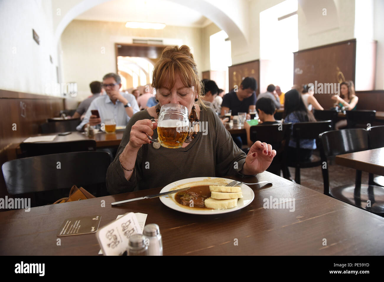 Donna con un bicchiere di birra tradizionale e classico cibo ceco al Lokal Dlouhaaa beer pub ristorante di Praga, Repubblica Ceca Foto Stock