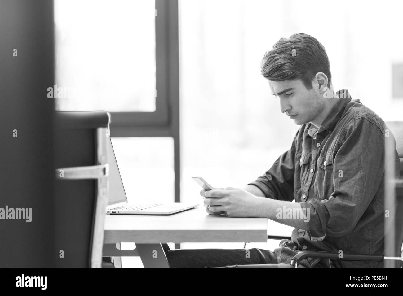Giovane imprenditore casual utilizza lo smartphone nell'ufficio di avvio Foto Stock