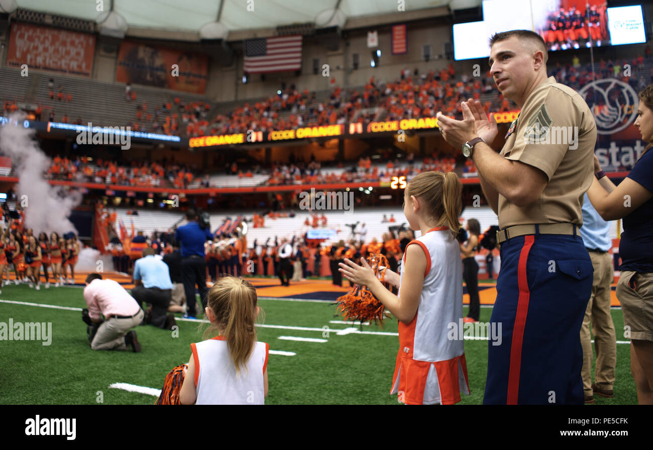 150919-N-PJ969-211 Siracusa, N.Y. (Sett. 19, 2015) - Staff Sgt. Giuseppe DiGirolamo e le sue figlie allietare dall'infield come la Syracuse University football team corre sul campo prima di prendere su Central Michigan University. DiGirolamo, che ha servito nella Marine Corps per dieci anni, è una centrale di New York e nativa è stata selezionata per essere la "Hometown Hero' per il gioco. (U.S. Foto di Marina di Massa lo specialista di comunicazione 2a classe Abe McNatt) Foto Stock