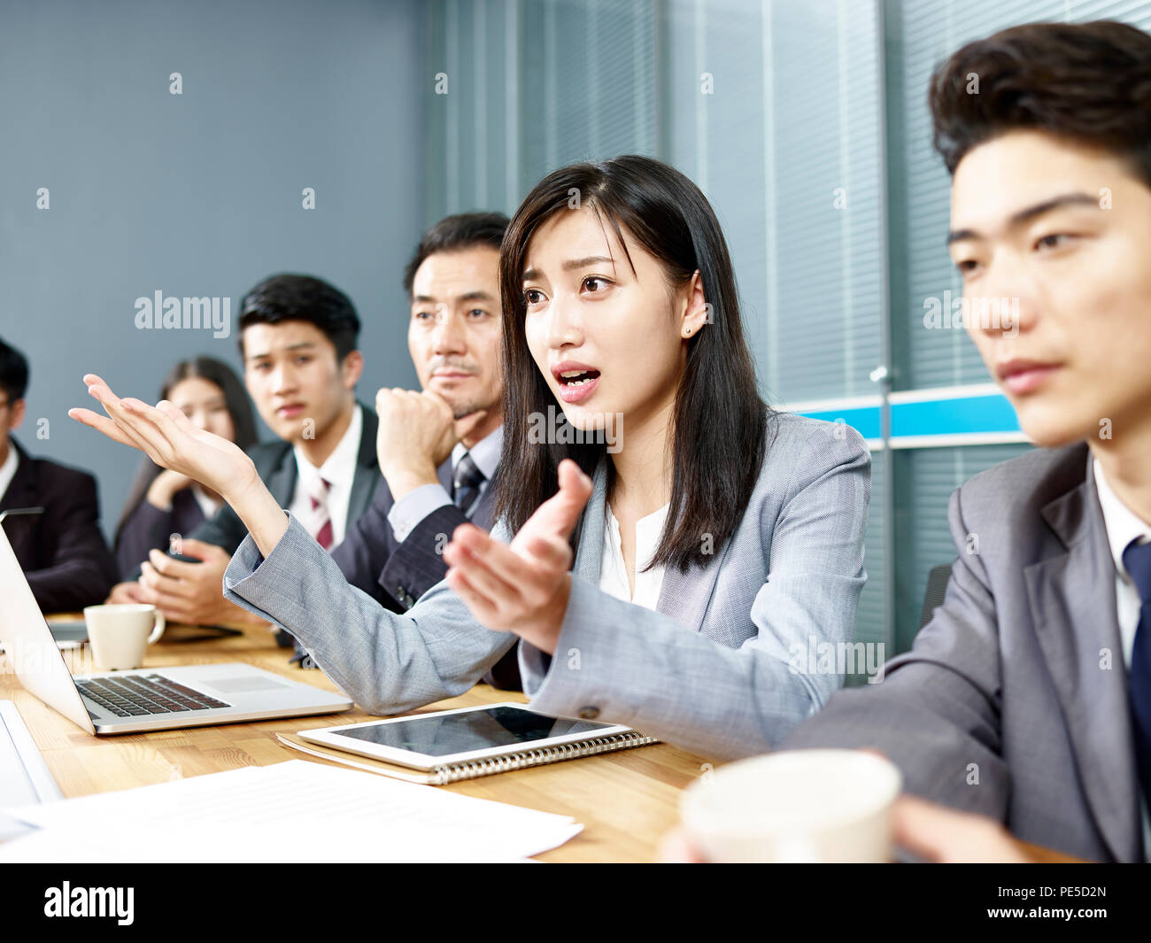 Giovani asian Business Woman Executive che si impegna in una accesa discussione durante la riunione. Foto Stock