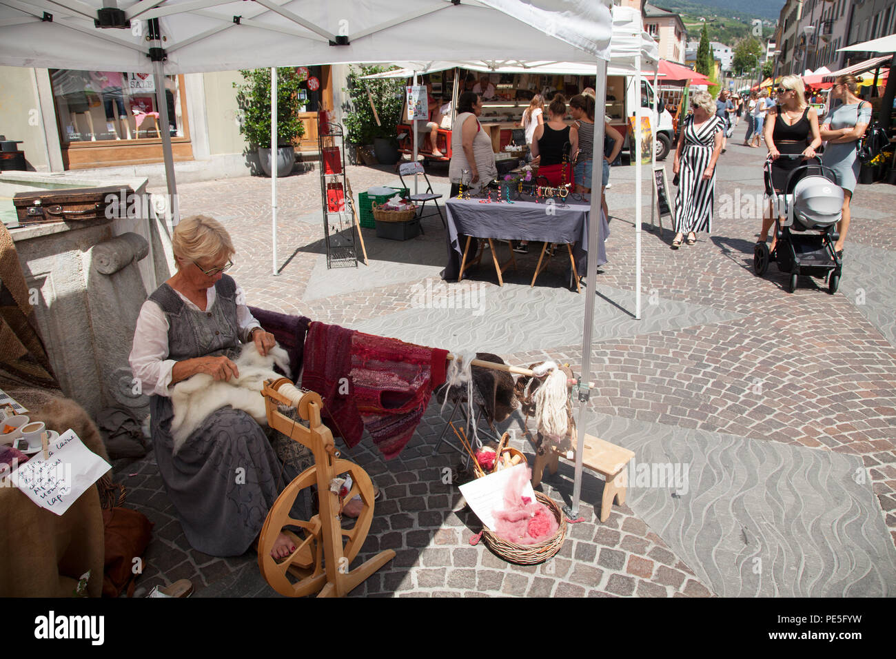 La donna gira i filetti con ruota di filatura sul mercato nella città svizzera di Sion Foto Stock