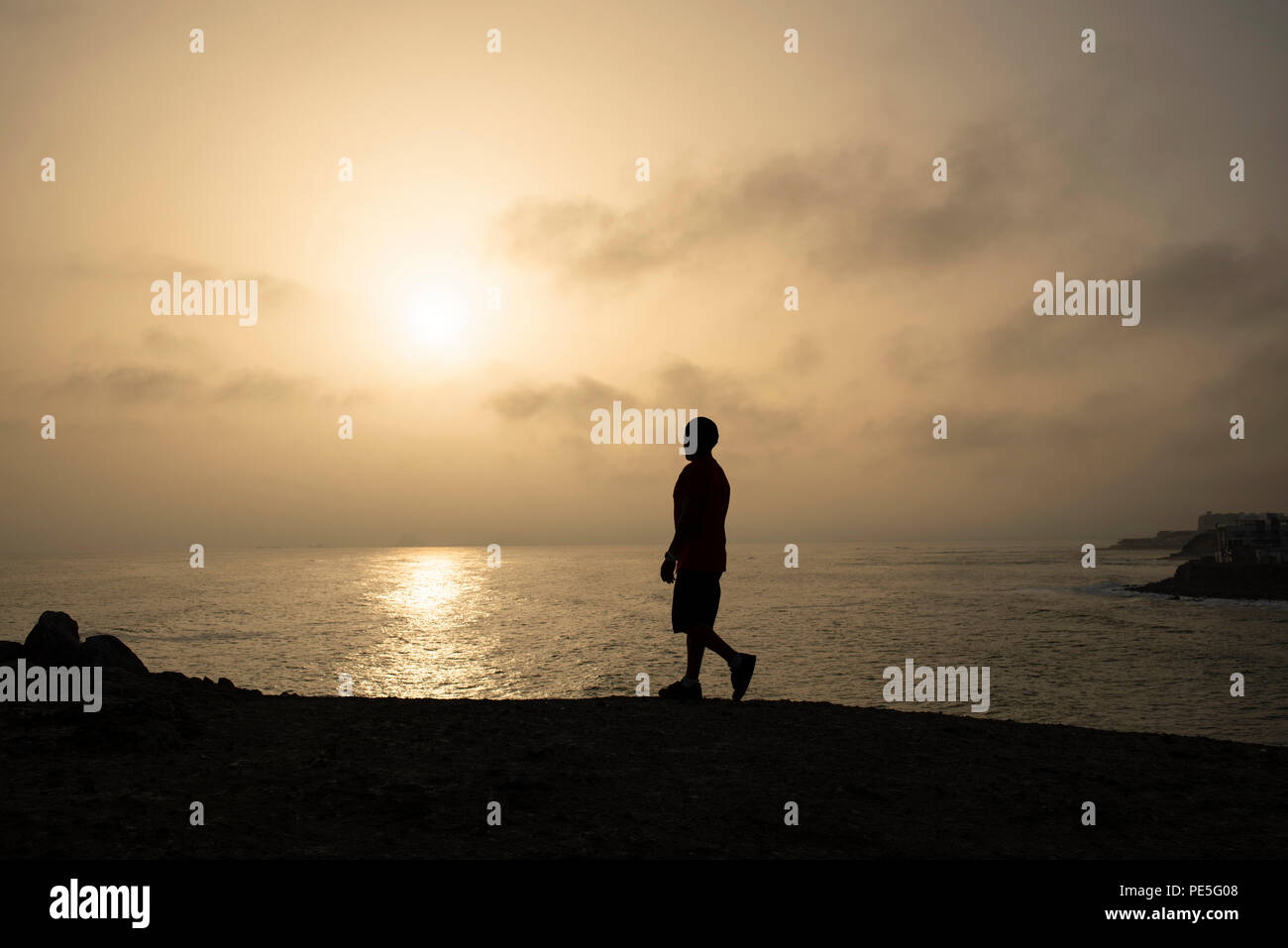 Silhouette di un ragazzo che cammina verso il sole su "La Isla' in Punta Hermosa Beach town. Misterioso, Golden Sunset. Provincia di Lima, Perù. Lug 2018 Foto Stock
