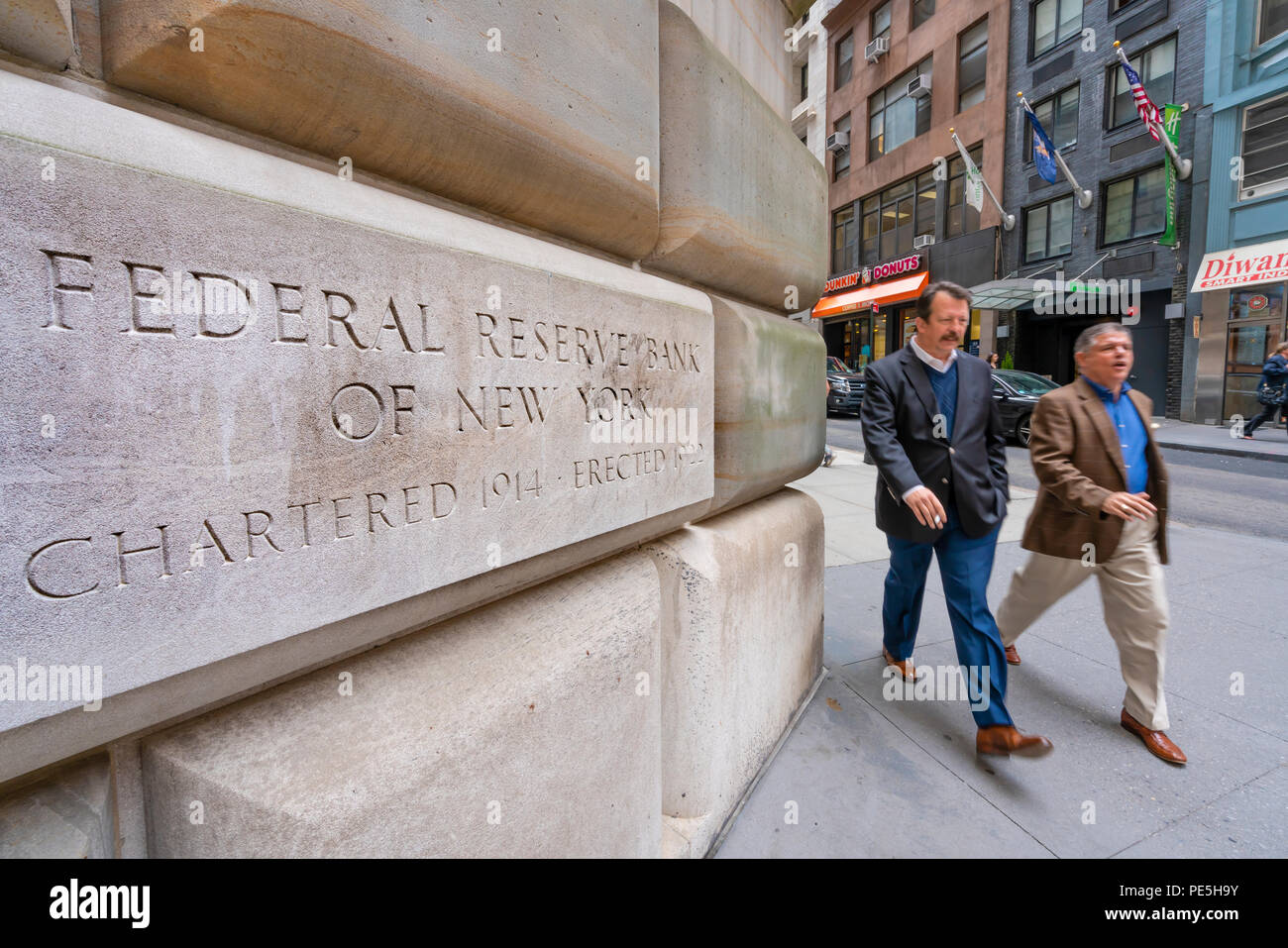 Uomo che cammina oltre la Federal Reserve Bank di New York Foto Stock
