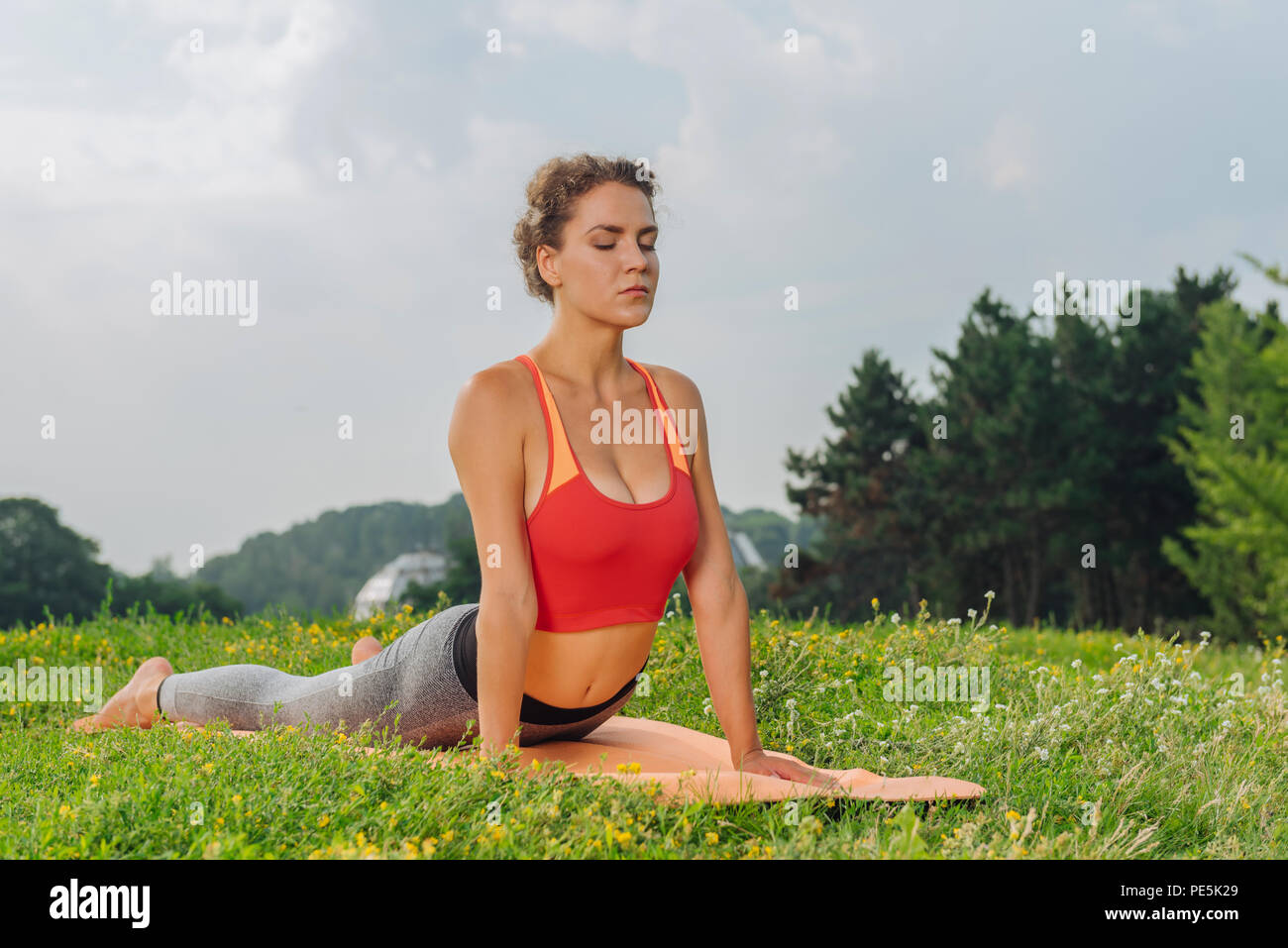 Curly donna chiudendo gli occhi mentre pensare positivo durante lo yoga Foto Stock
