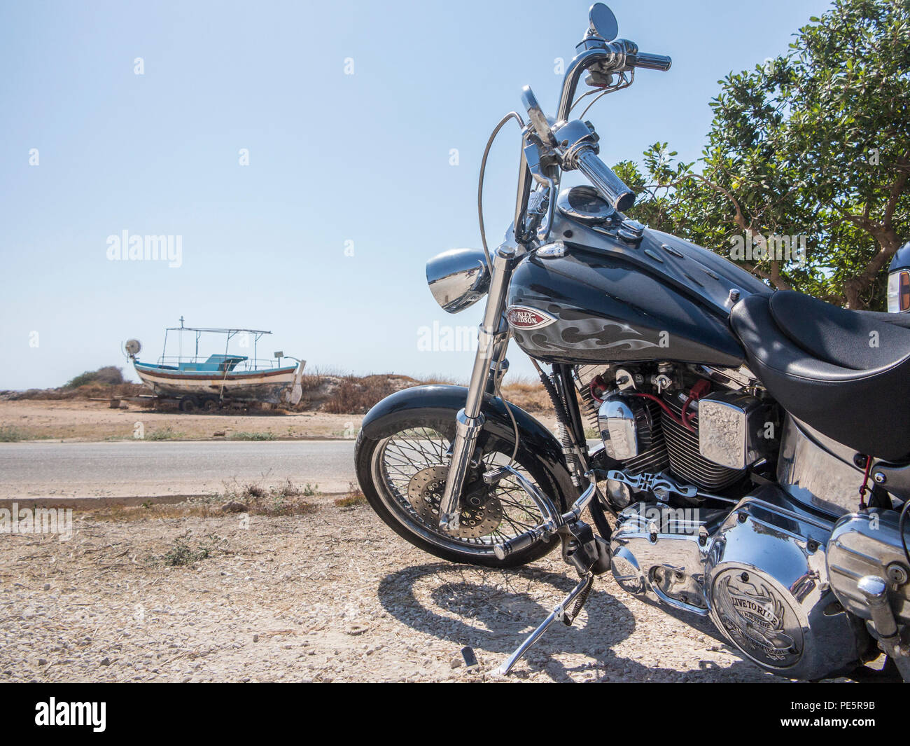Una Harley Davidson Moto con una barca da pesca nella distanza sulla costa  in un paese caldo Foto stock - Alamy