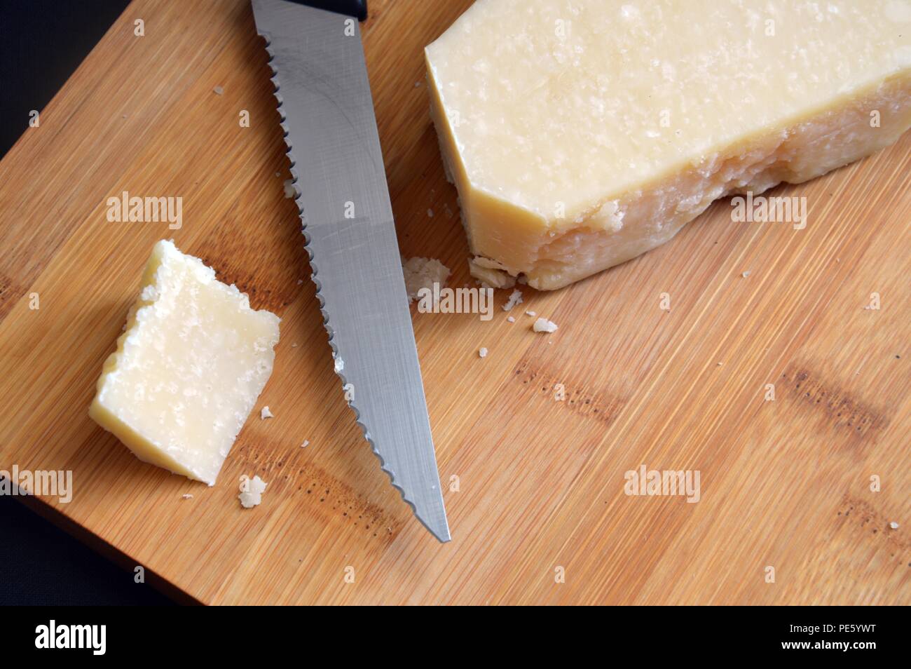 Pezzo di formaggio grana padano sul tagliere di legno Foto Stock