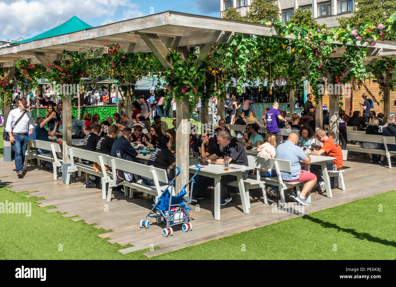 I visitatori e gli artisti interpreti o esecutori in Edinburgh Festival Fringe rilassarsi nel pomeriggio di sole in Bristo Square nel centro della citta'. La Scozia, Regno Unito. Foto Stock