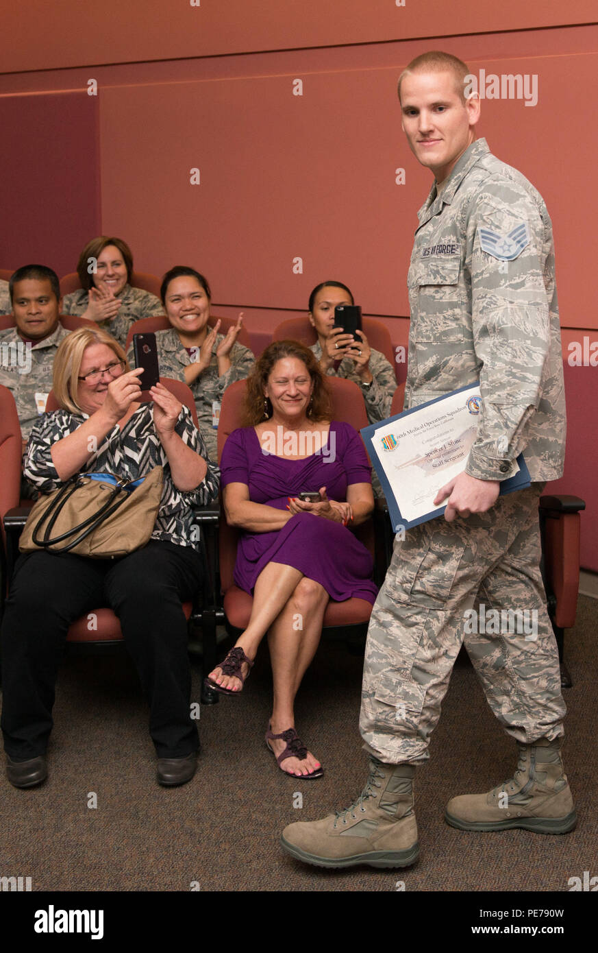 Joyce Eskel, sinistra, prende una foto di suo figlio, Staff Sgt. Spencer Pietra, a destra seguendo la sua promozione nel corso di una cerimonia al Travis Air Force Base in California, Ottobre 30, 2015. In seguito alla sua promozione a senior airman minuti prima pietra fu promosso al rango di personale il sergente per ordine di Air Force capo del personale gen. Mark A. Welsh III. Secondo Air Force istruzione 36-502, il capo del personale della Air Force ha il potere di promuovere qualsiasi elemento arruolato al grado superiore. La pietra divenne il destinatario del raro onore seguendo il suo azioni eroiche nel mese di agosto quando lui e due amici t Foto Stock