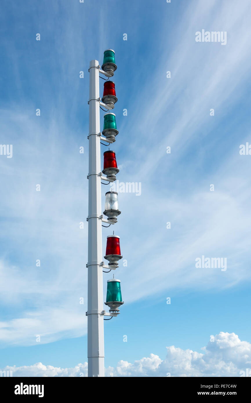 Il verde e il rosso marittimo lampade di segnale su un metallo bianco colonna contro una soleggiata cielo blu. Foto Stock
