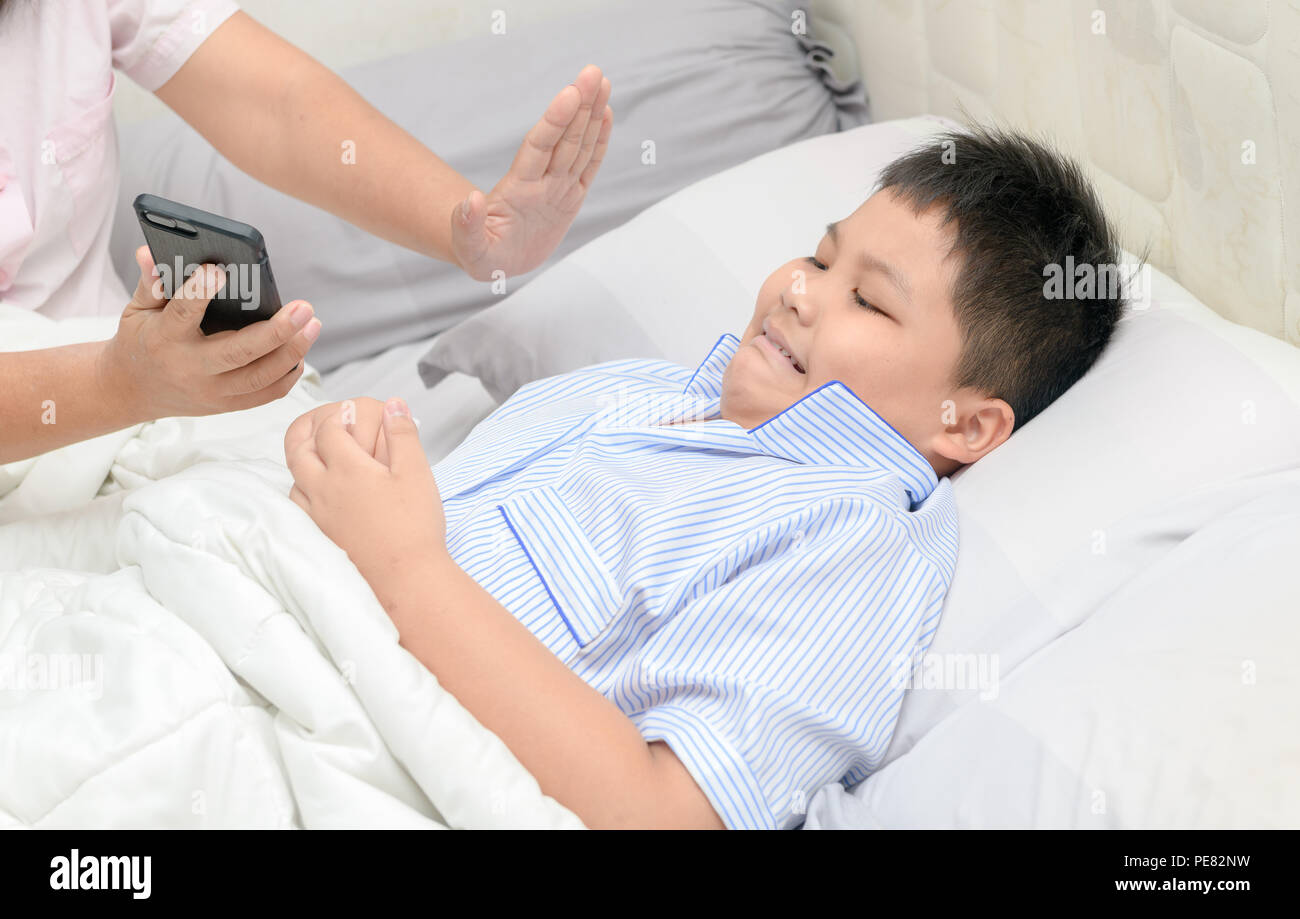 La madre ha ordinato i bambini non giocano con i telefoni cellulari per lungo tempo, problema sul letto, health care concept Foto Stock