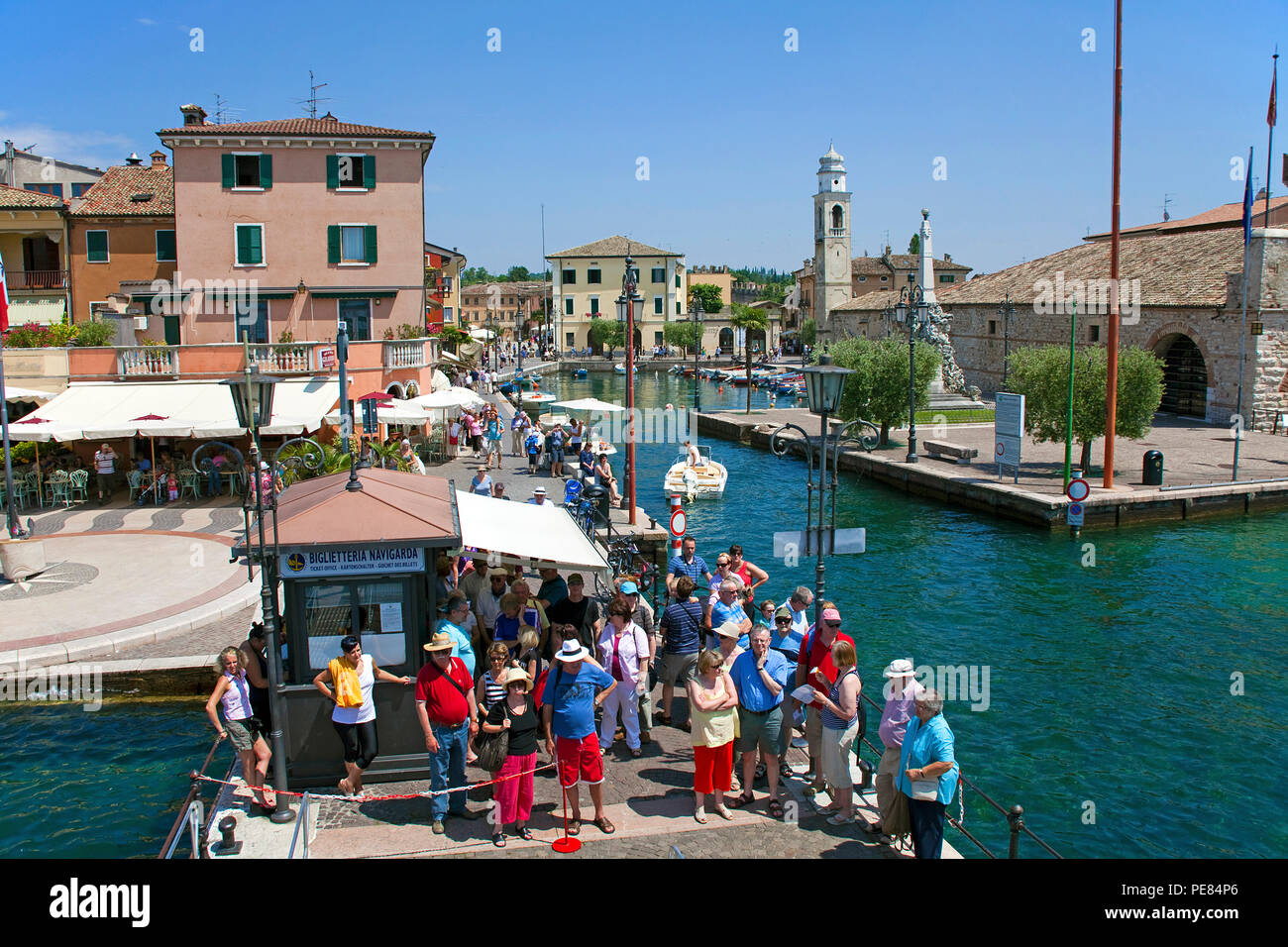 I turisti in attesa sul molo per i traghetti, ingresso del porto di Lazise, sul lago di Garda, provincia di Verona, Italia Foto Stock