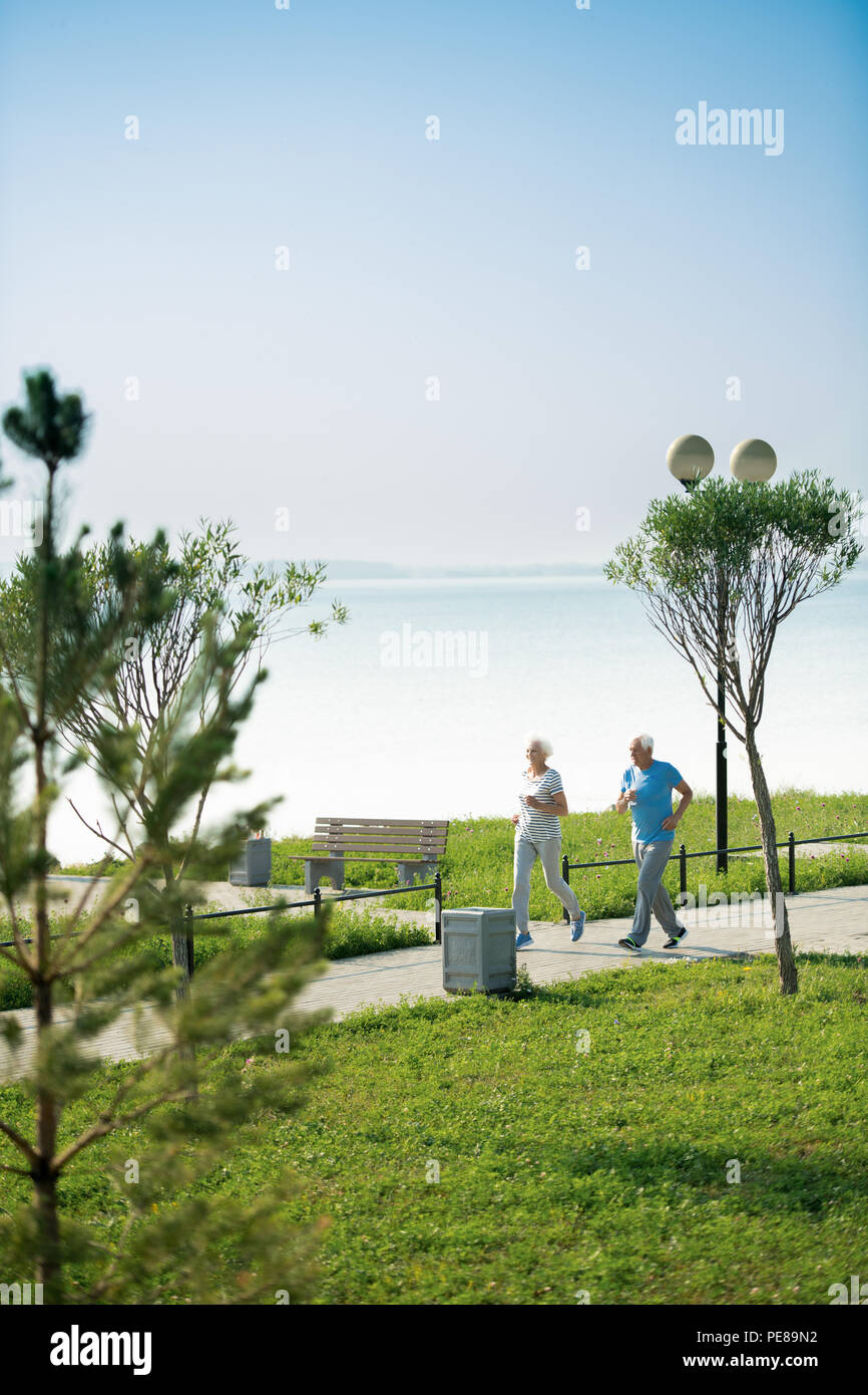 Coppia senior in esecuzione dal lago Foto Stock