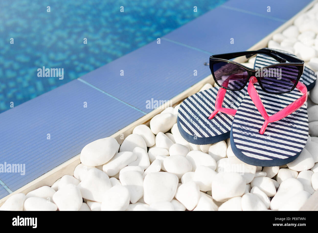 Flip-flop e occhiali da sole a bordo della piscina. Close-up. Foto Stock