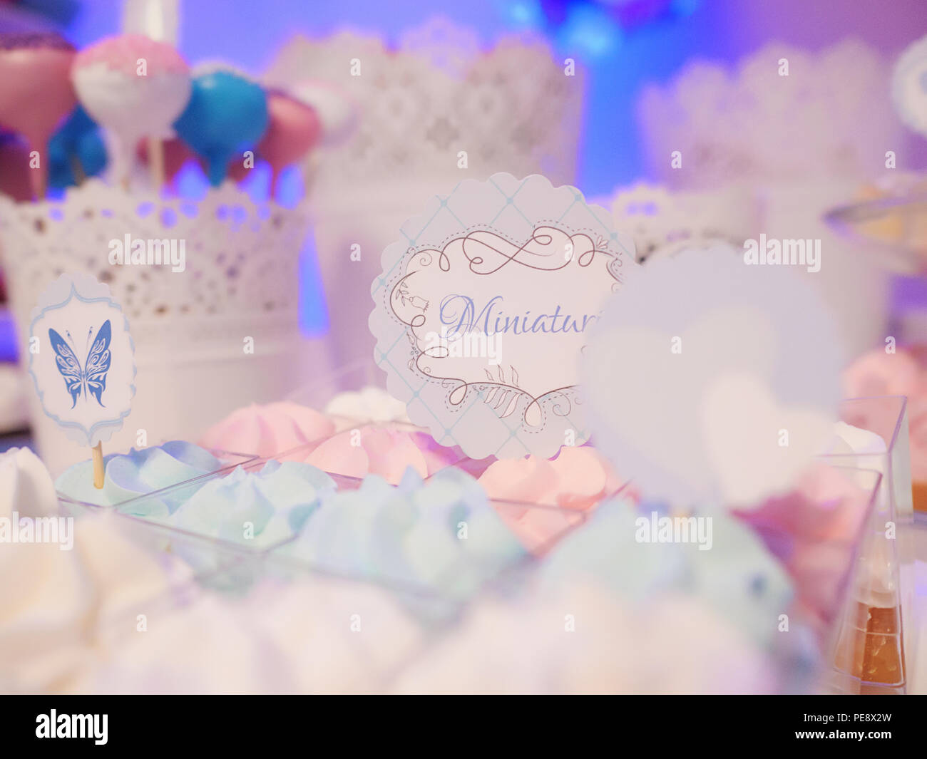 Messa a fuoco selettiva su un display di dolci con un grande assortimento di meringhe e torte pop, con butterfly e piccole etichette di messaggio Foto Stock