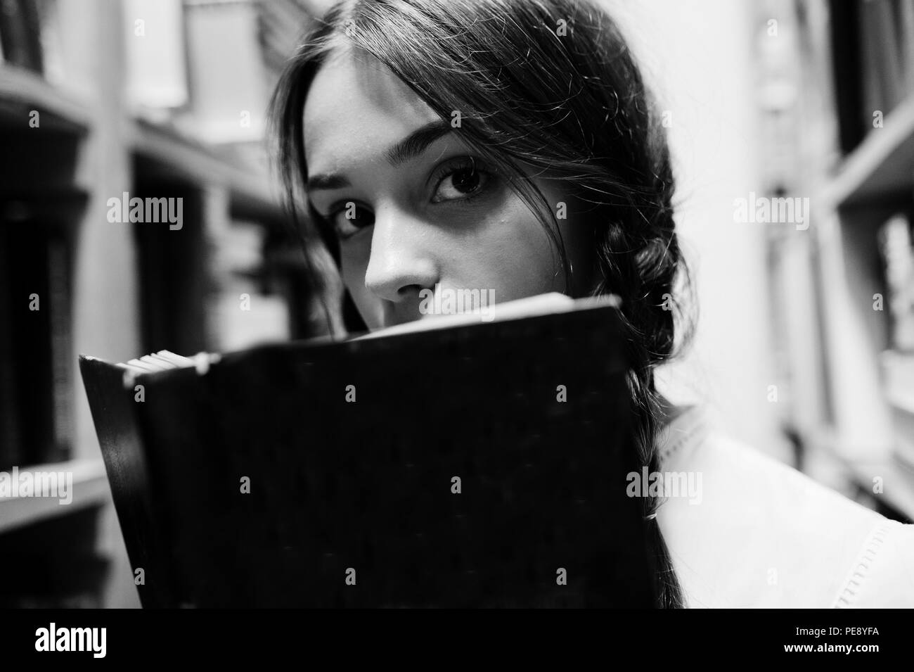 Ragazza con pig-tail in camicia bianca alla vecchia libreria. Foto Stock