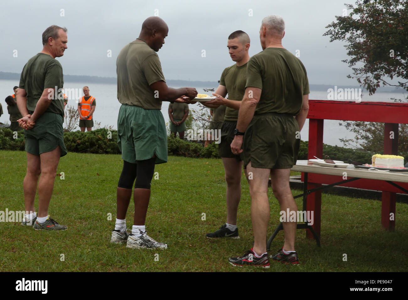 Più di 6.000 marines con seconda divisione Marine guarda su come Master Gunnery Sgt. Jerry Morris (centro sinistra) passa una fetta di torta di compleanno a PFC. Christopher Rizzi (centro destra) a seguito di una divisione ampia esegui per celebrare il Marine Corps' 240th compleanno di Camp Lejeune, N.C., nov. 9, 2015. Morris, identificato come il più antico marino in unità, ha onorato la tradizione di passare la torta per il più giovane Marine, Rizzi, a significare il passaggio di esperienze e conoscenze per la più recente generazione di Marines. (U.S. Marine Corps foto di Cpl. Sullivan Laramie/rilasciato) Foto Stock