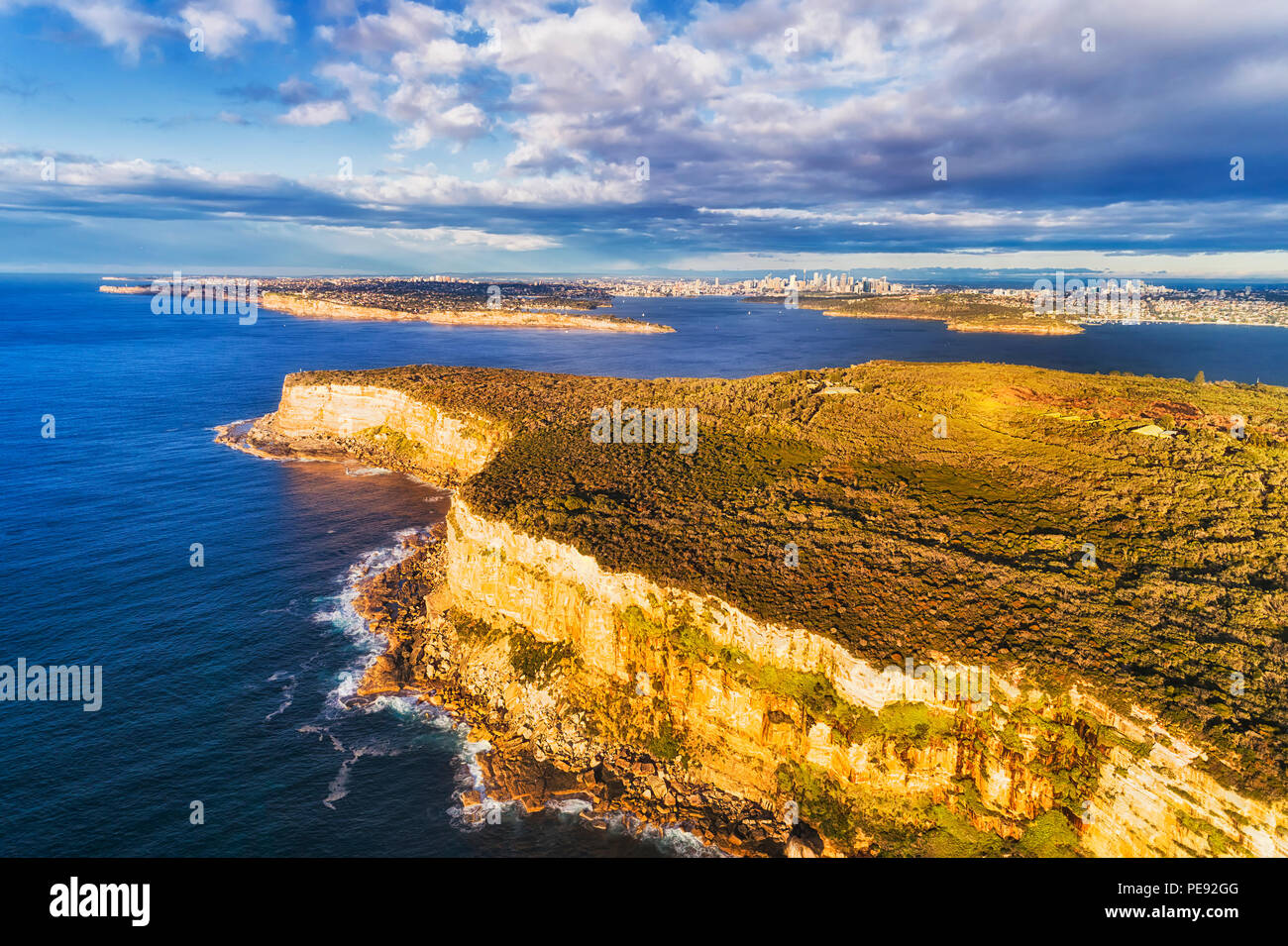 Ripida endges di North Head altopiano di arenaria a guardia del Sydney Harbour da aperto oceano pacifico su una mattina di sole con vista della città lontana CBD. Foto Stock