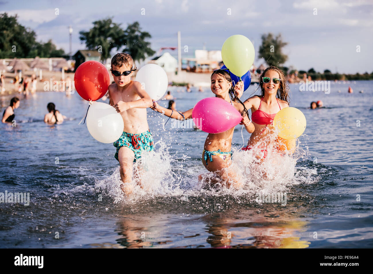 Dei bambini felici giocando con palloncini in mare. Bambini il divertimento all'aperto. La vacanza estiva e uno stile di vita sano concetto Foto Stock