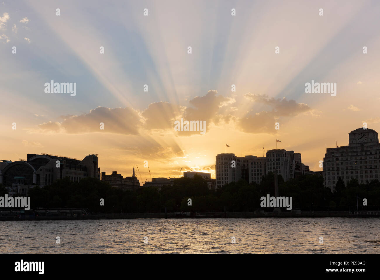 Raggi crepuscolari visto dalla riva sud del fiume Tamigi come il sole tramonta a Londra, nel Regno Unito nel mese di agosto 2018 Foto Stock