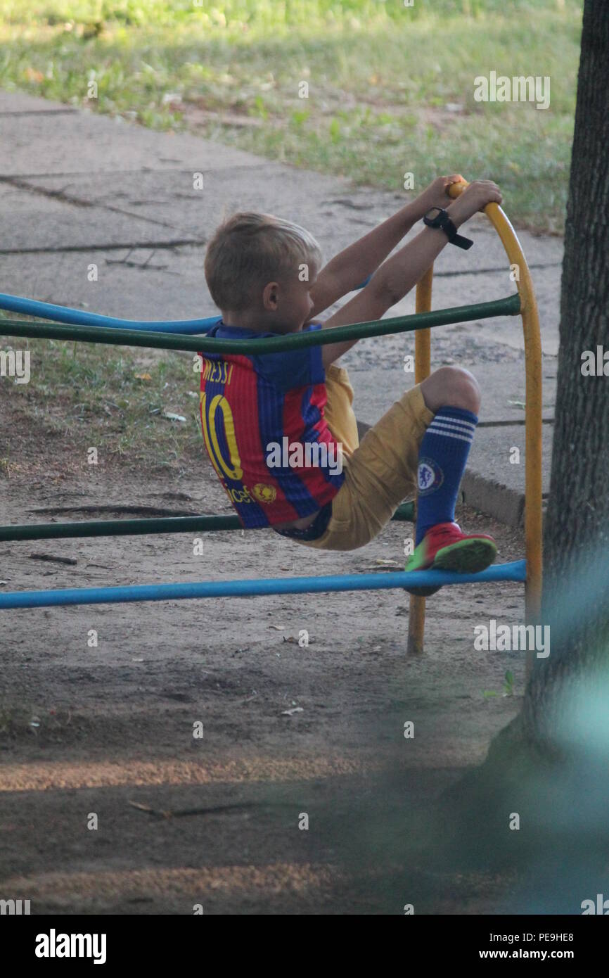 Little Boy nel calcio forma fatta mattina esercizio sul parco giochi in un caldo giorno d'estate Foto Stock