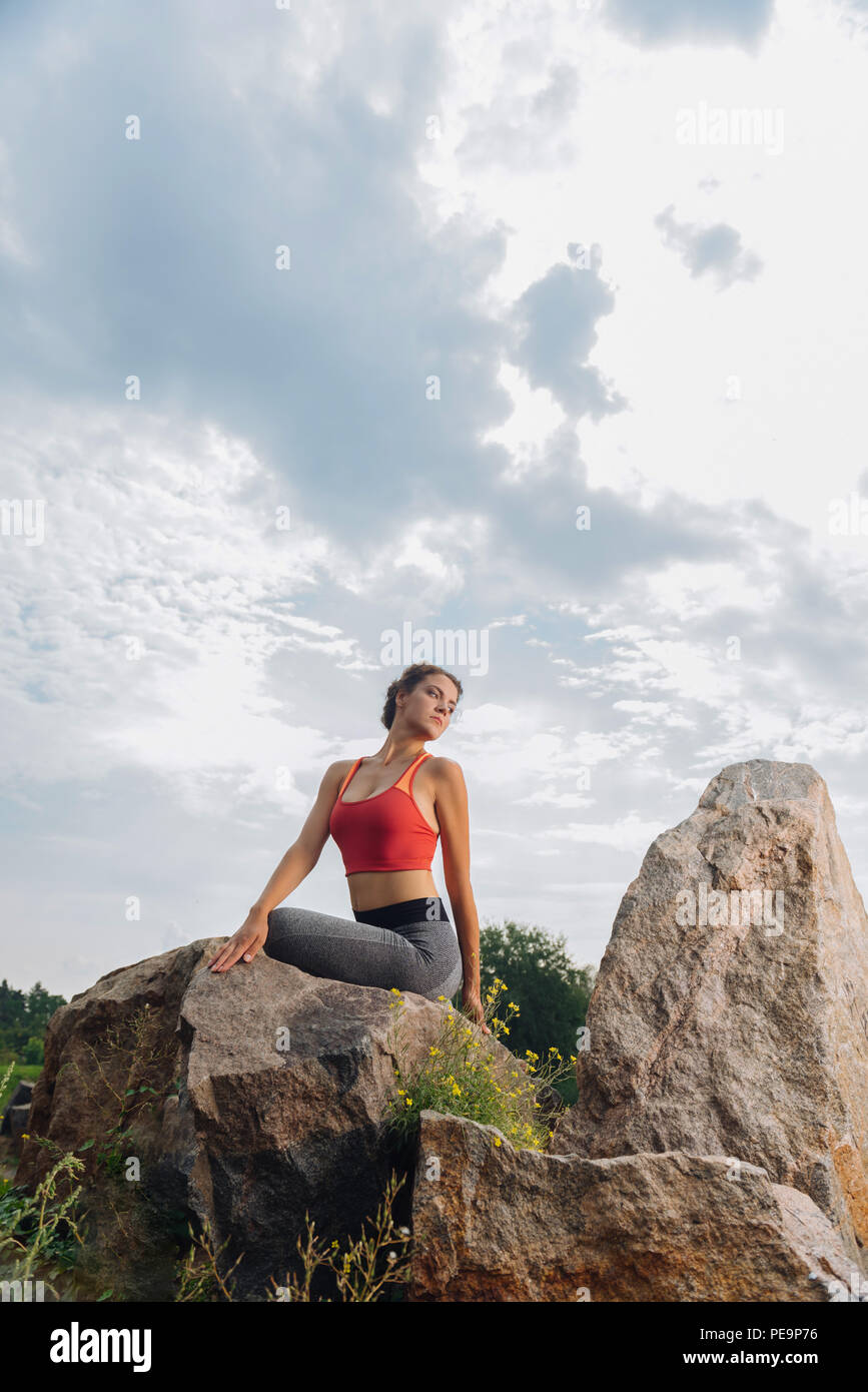 Donna godere dell'aria fresca mentre lo stiramento nei pressi di rocce Foto Stock