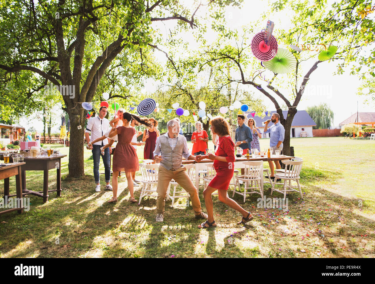 Un senior coppia e famiglia danza su un party in giardino al di fuori nel cortile. Foto Stock