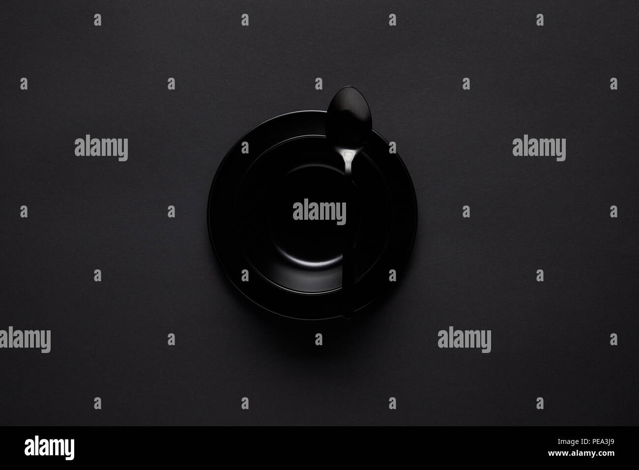 Vista superiore del vaso nero e cucchiaio sulla tavola nera, concetto minimalista Foto Stock