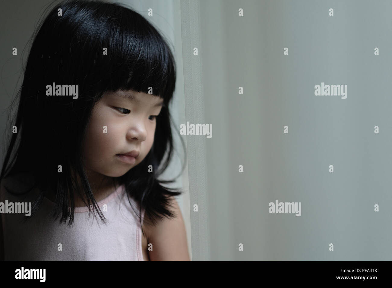 Triste lonely bambina in piedi accanto a una finestra Foto Stock