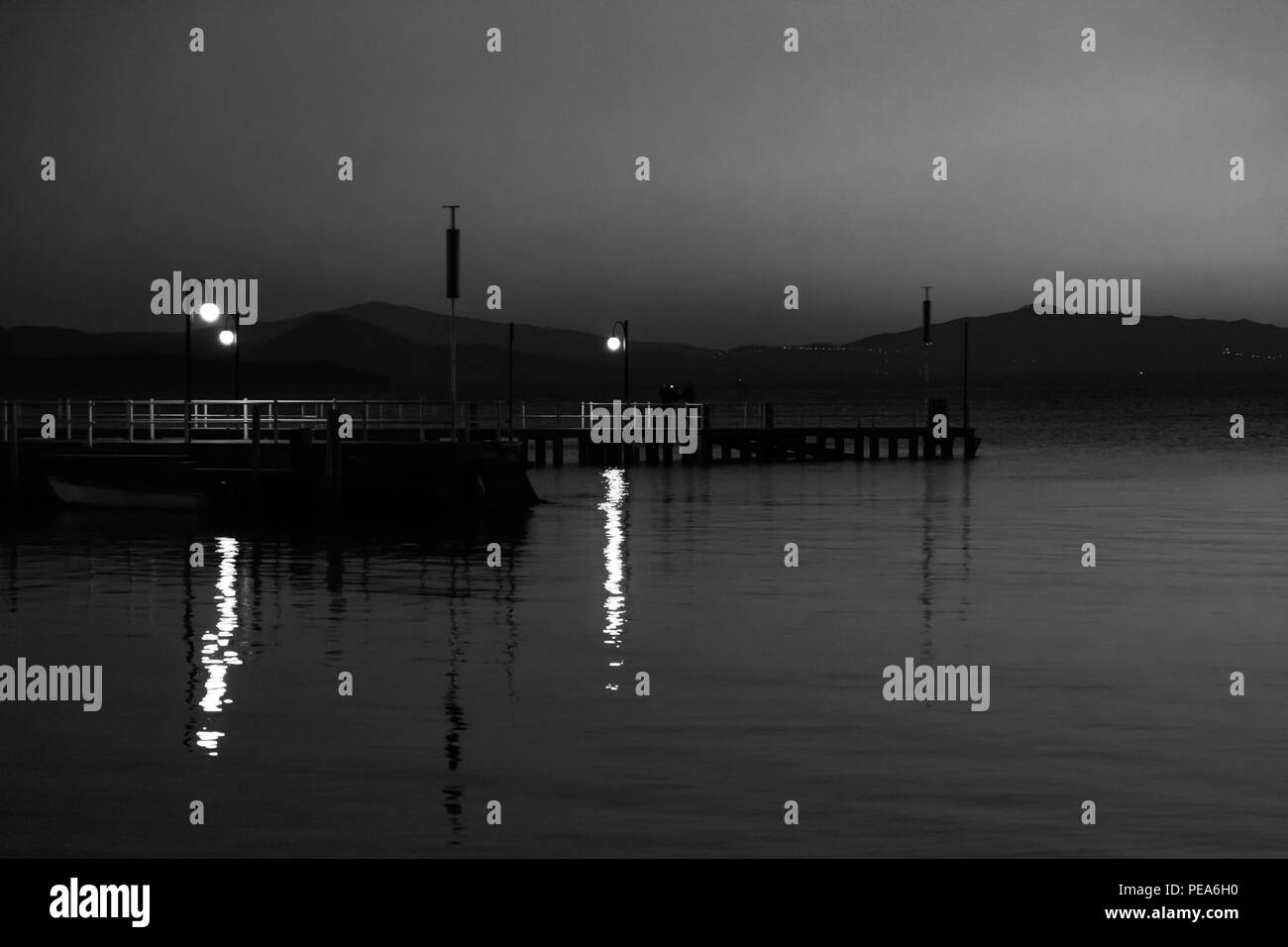 Alcune persone su un molo presso il lago Trasimeno (Umbria, Italia) al tramonto Foto Stock