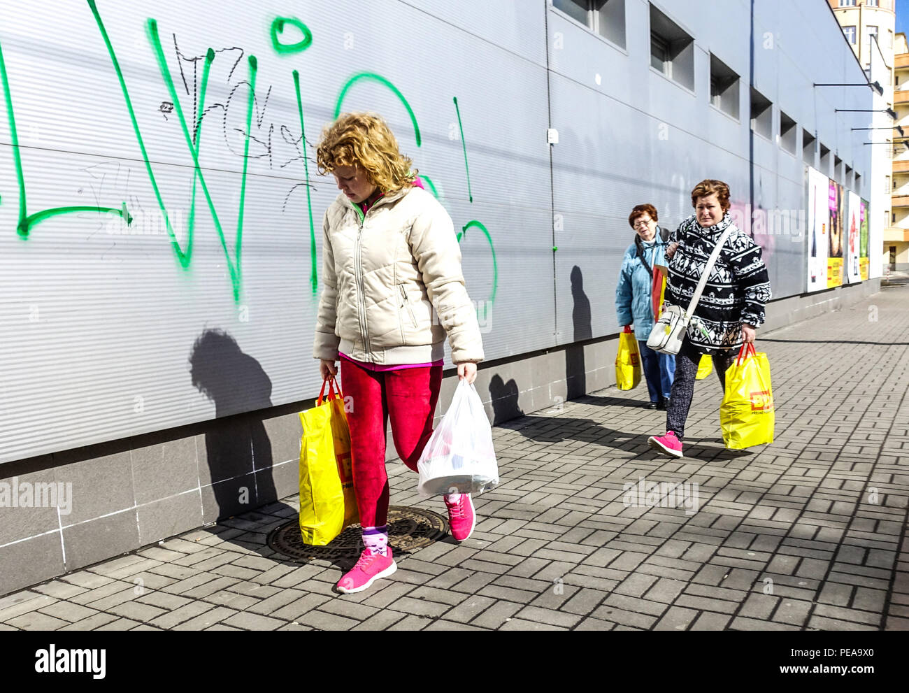 Le donne con piena di shopping di acquisto dei sacchetti di plastica andare fuori del supermercato, Repubblica Ceca Foto Stock