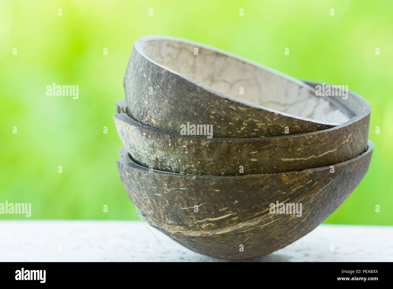 Pila di guscio di noce di cocco bocce sul fogliame verde dello sfondo. Abilità artigiana materiali eco-compatibili stoviglie. Pulire il concetto di mangiare. Banner Poster w Foto Stock